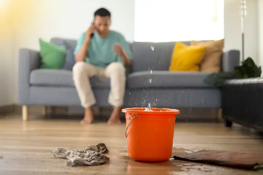 Person calling plumber while water is leaking from the ceiling.