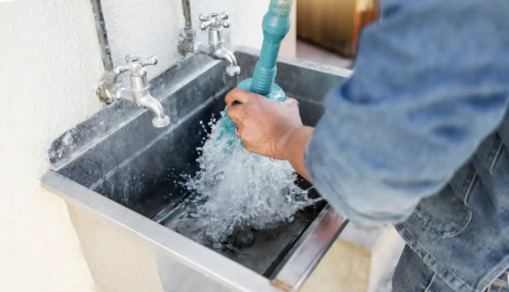 Plumber de-clogging Industrial sink with a hand plunger